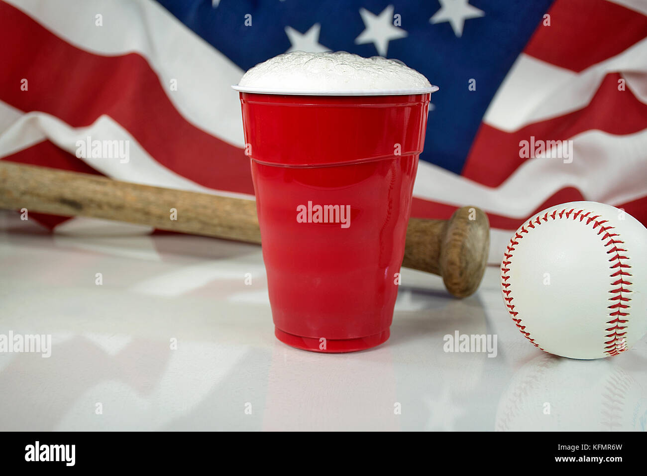 Bier in rot Tasse mit Baseball und hölzerne Fledermaus mit amerikanischer Flagge im Hintergrund Stockfoto