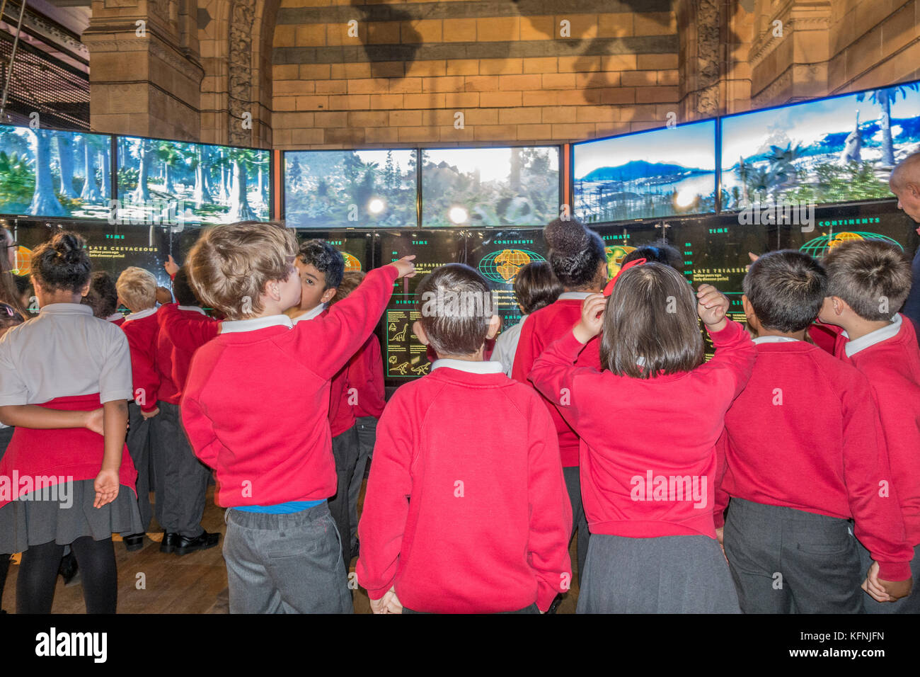 Aufgeregt Schulkinder in Uniform, auf Klassenfahrt, Anzeigen von Informationen zeigt am Natural History Museum, Kensington, London, England, UK. Stockfoto