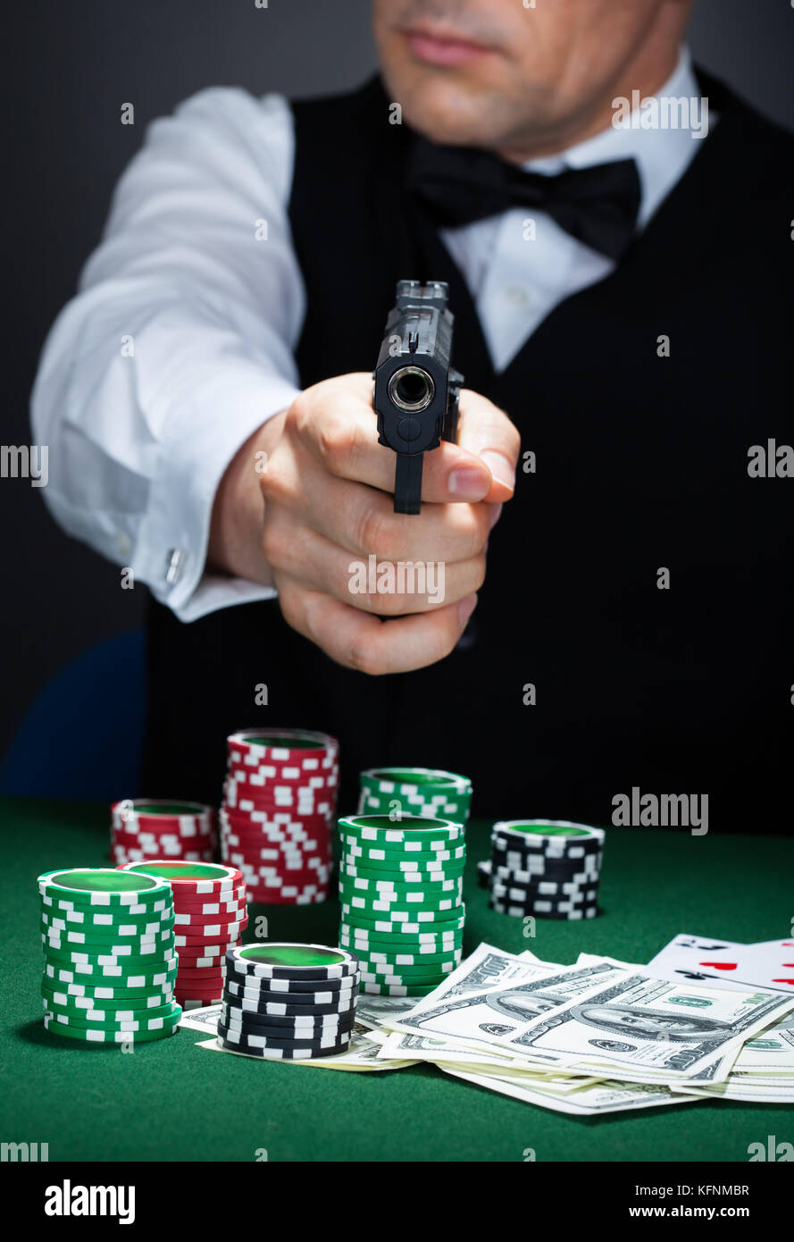 Croupier mit Stapel von Token-Chips und Banknote auf dem Tisch mit einem Gewehr zielen Stockfoto