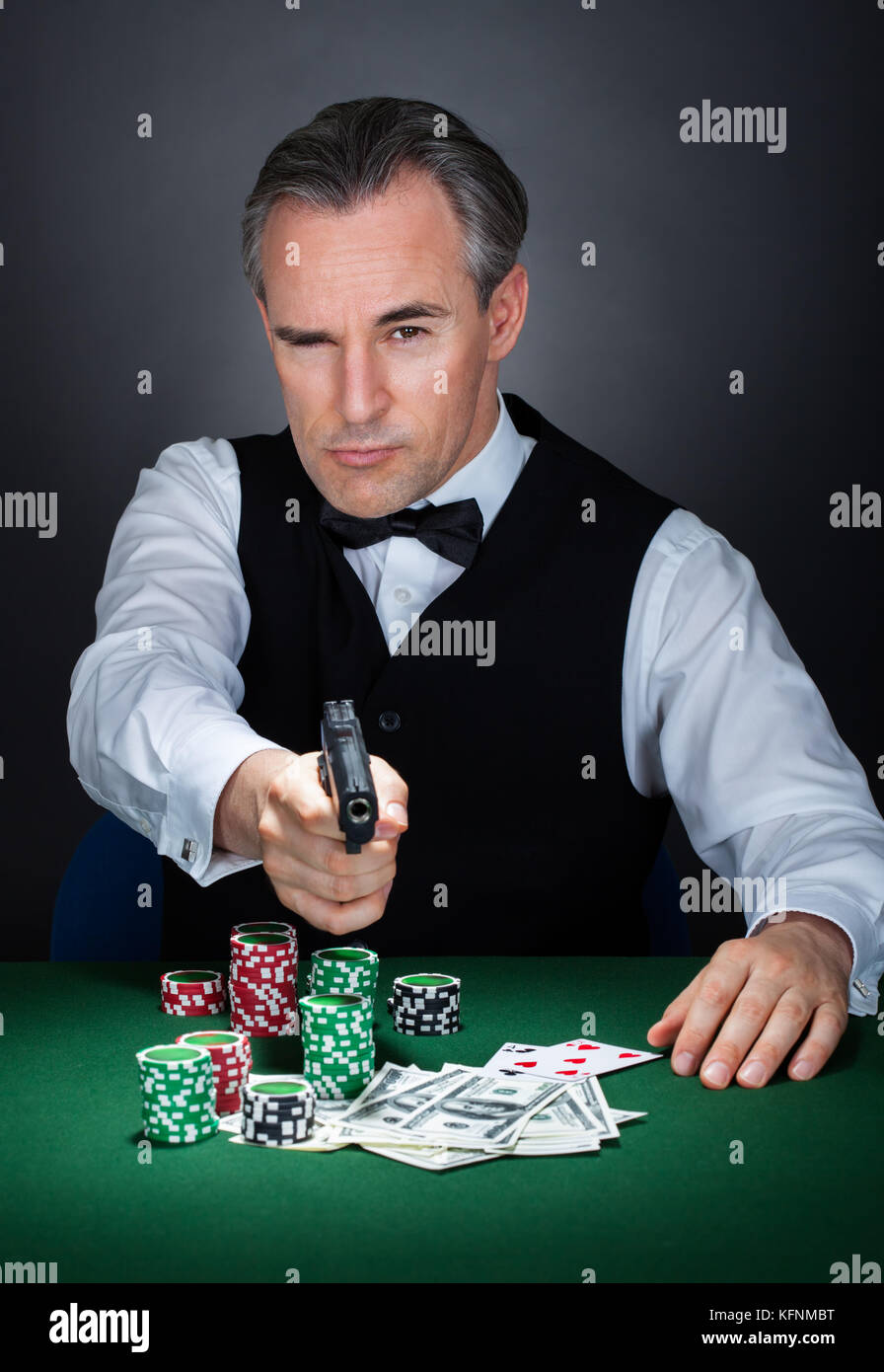 Croupier mit Stapel von Token-Chips und Banknote auf dem Tisch mit einem Gewehr zielen Stockfoto