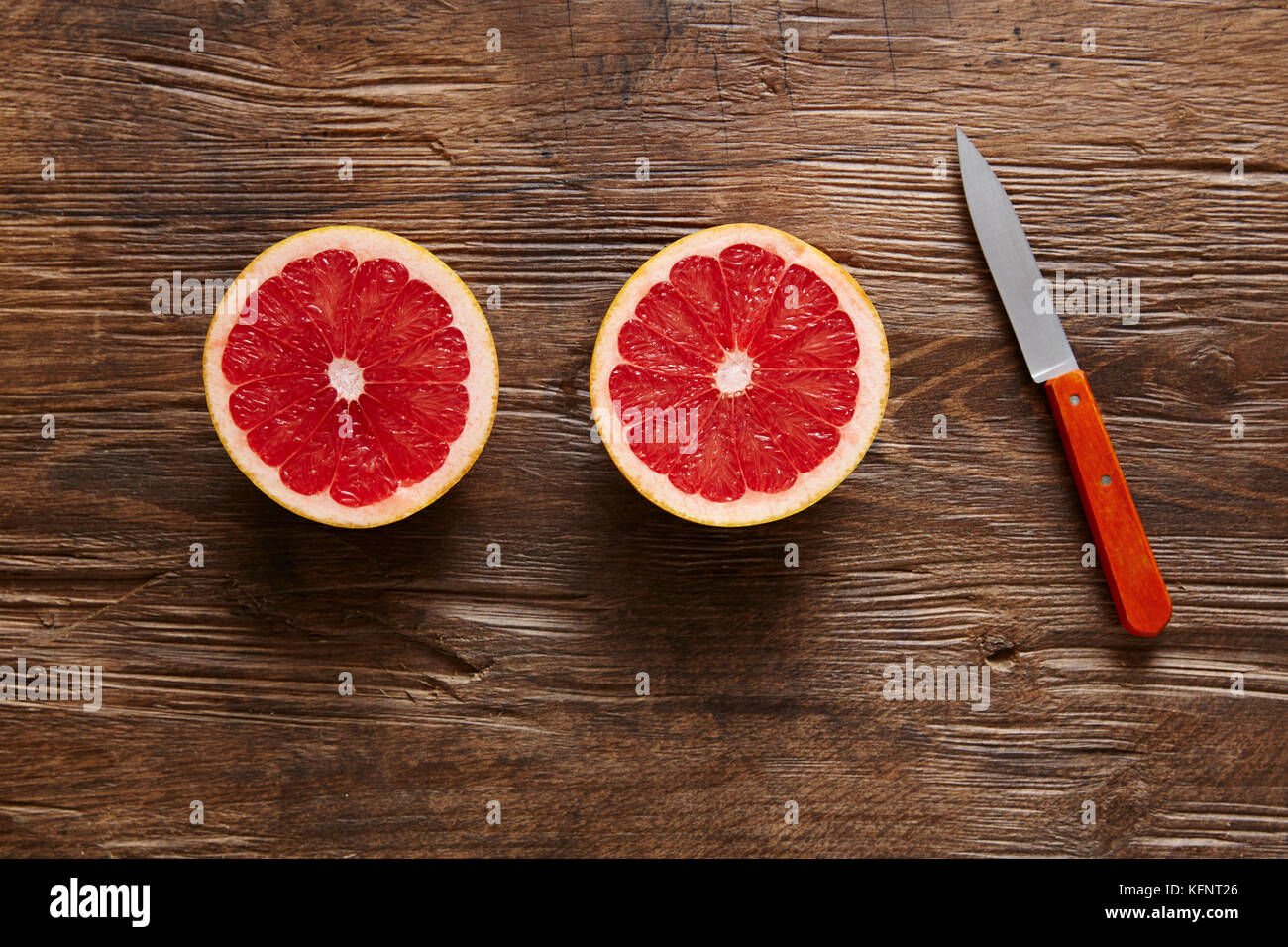 Zwei Hälften von geschnittenen Grapefruit mit Messer Stockfoto