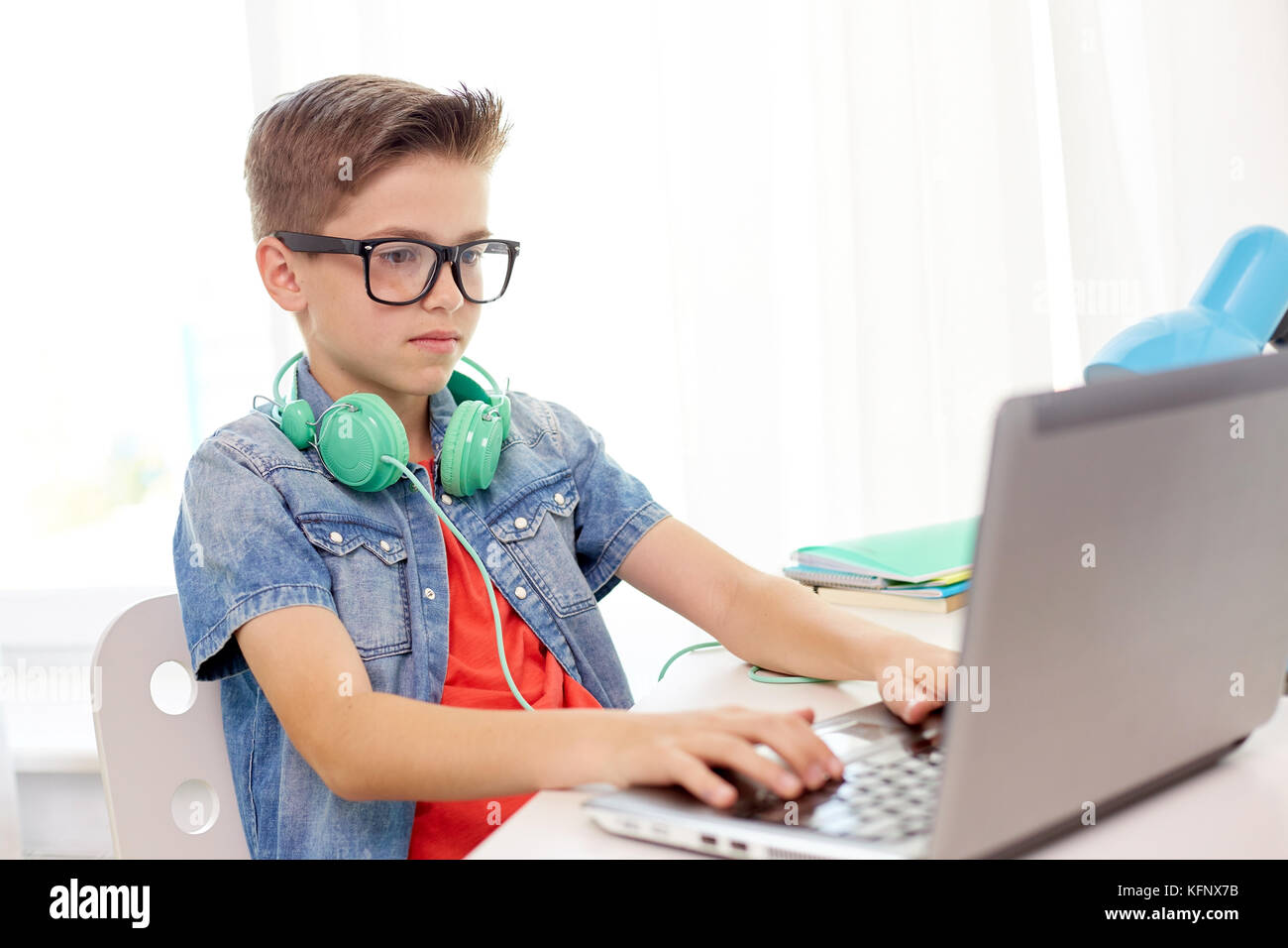 Schüler Junge in Gläser Tippen auf Laptop zu Hause Stockfoto