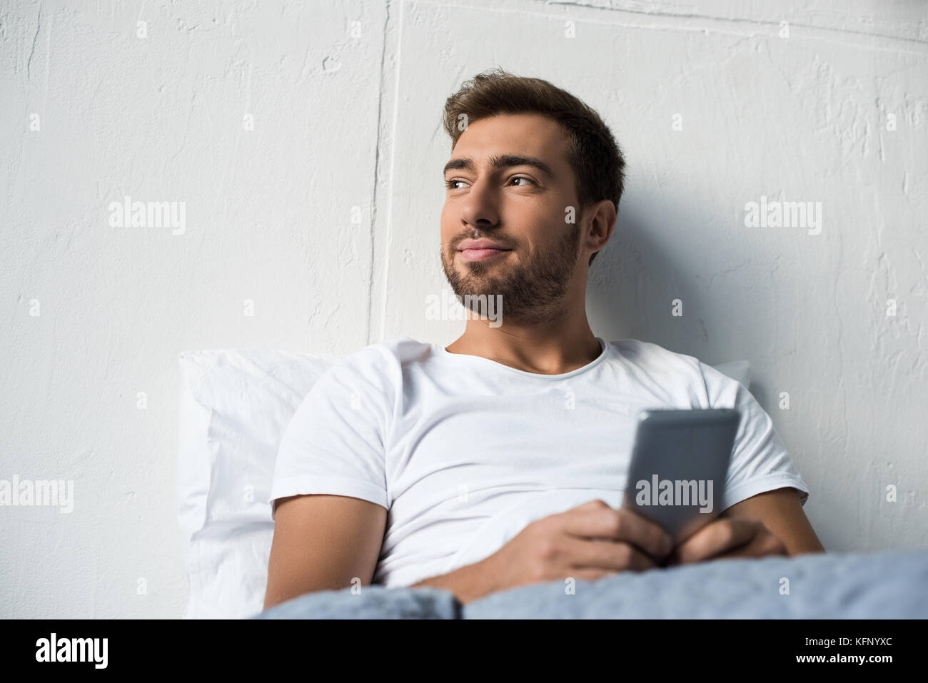 Mann mit im Bett smartphone Stockfoto