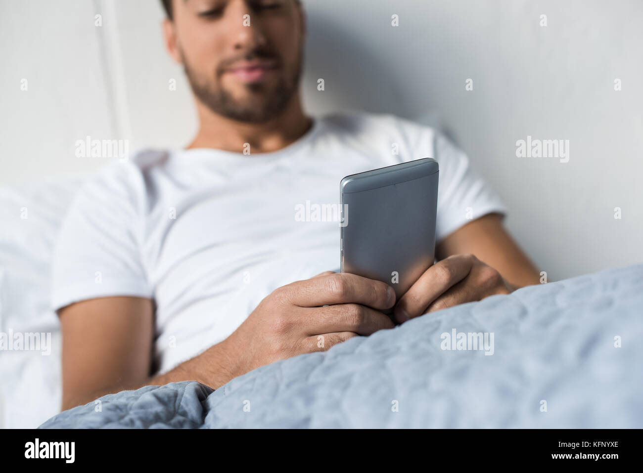 Mann mit im Bett smartphone Stockfoto