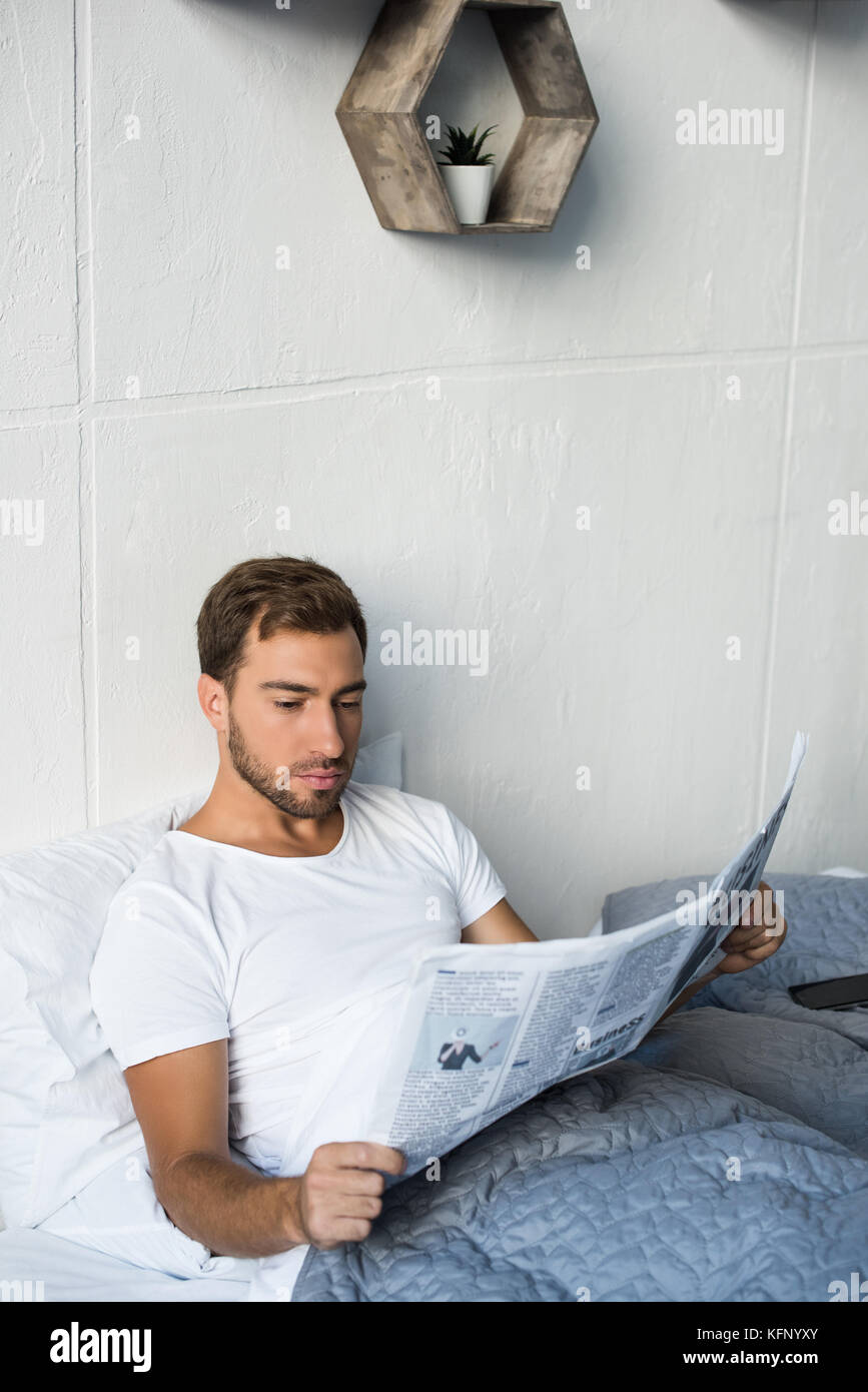 Mann im Bett und liest Zeitung Stockfoto
