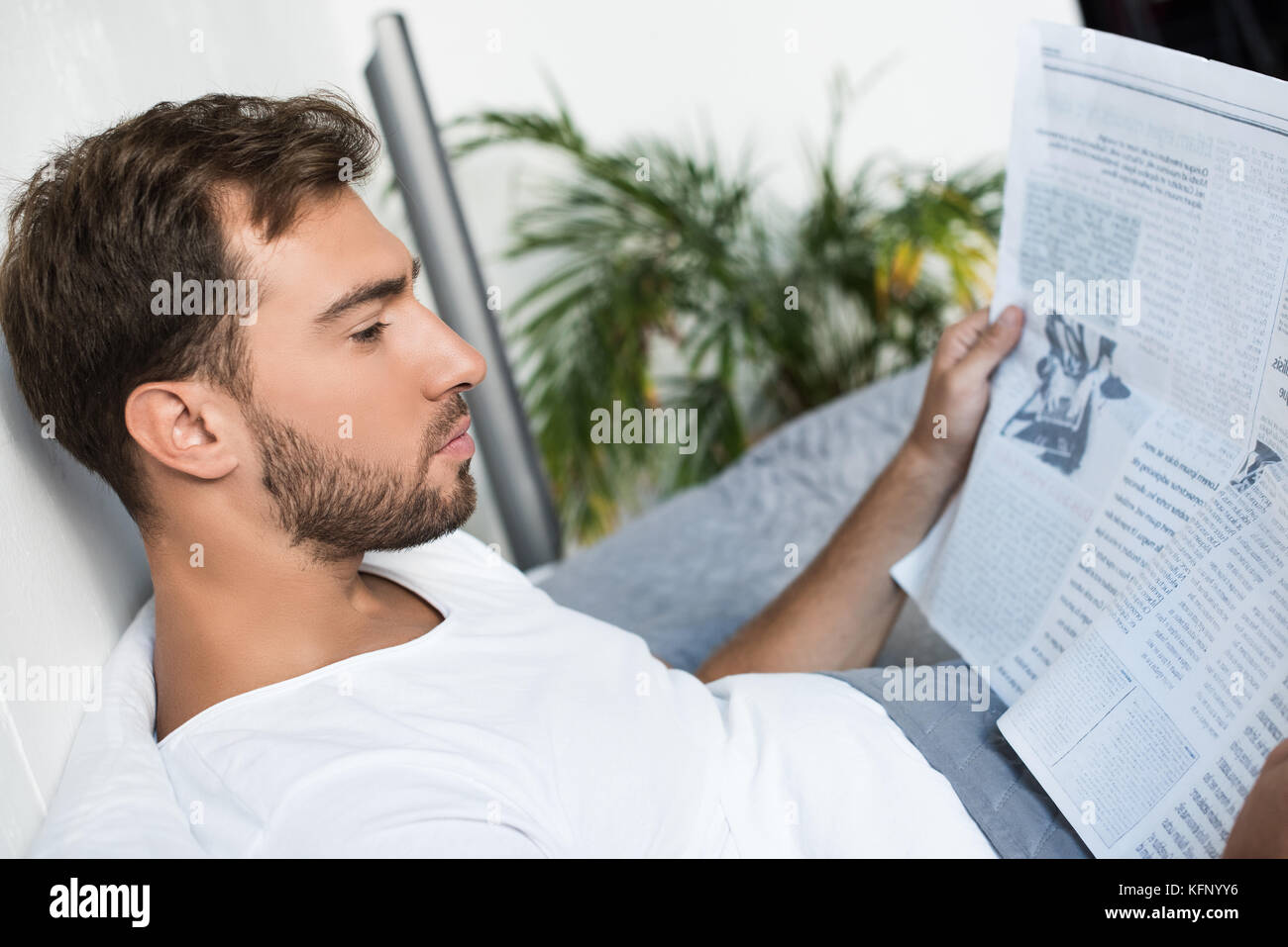 Mann im Bett und liest Zeitung Stockfoto