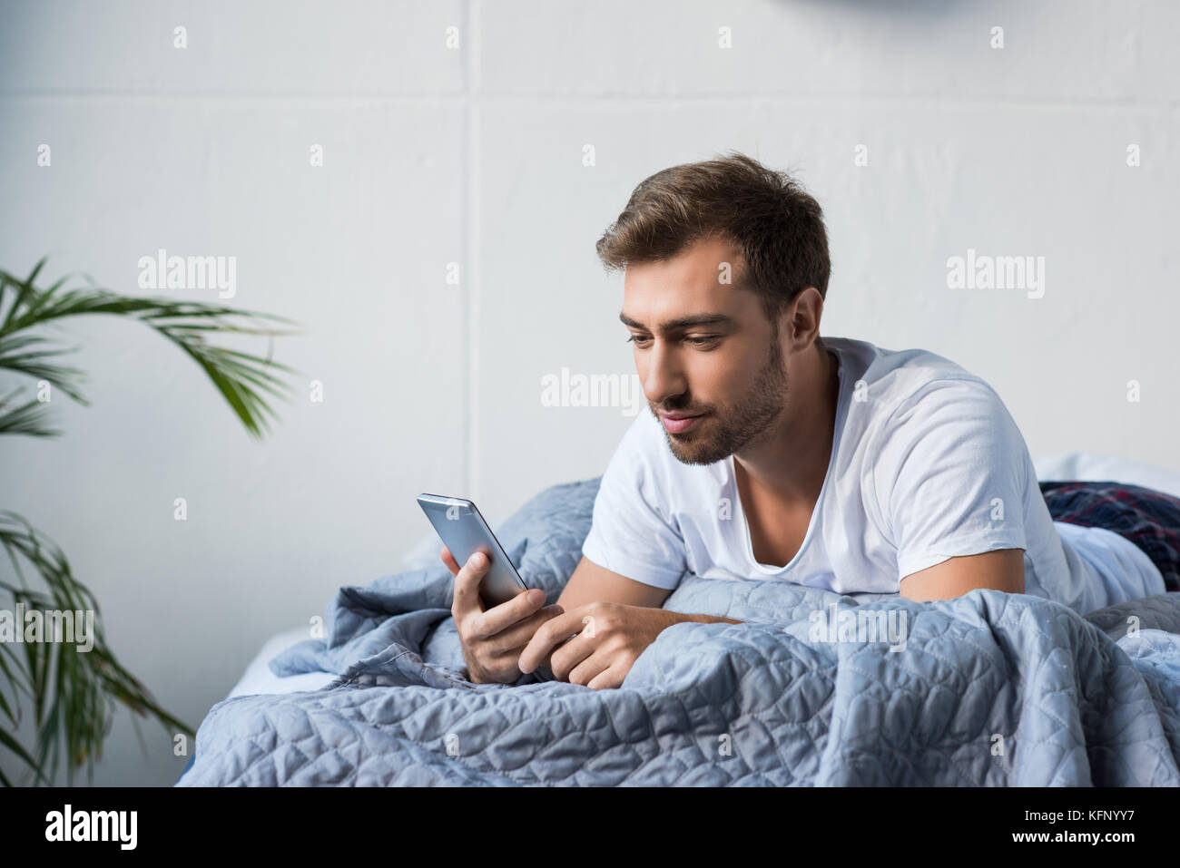 Mann im Bett mit Smartphone Stockfoto