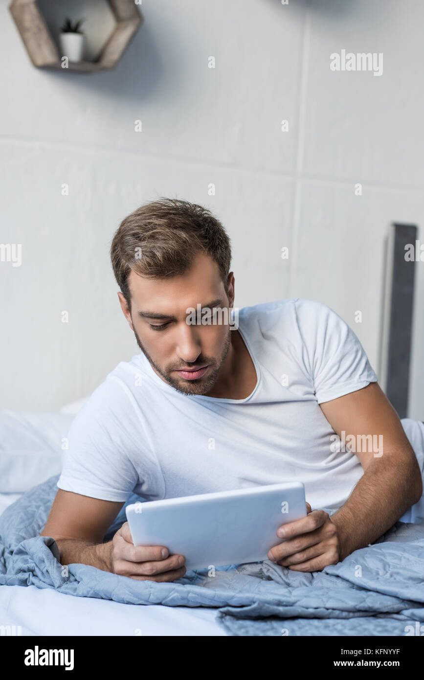 Mann im Bett mit digitalen Tablet Stockfoto
