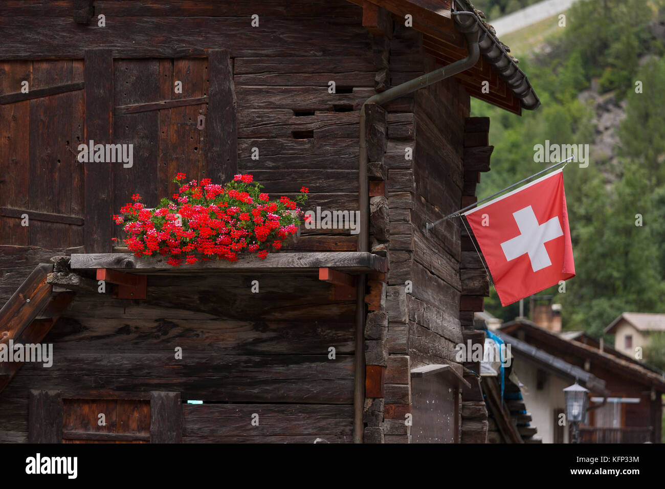 Herbriggen, Schweiz - traditionelles Gebäude aus Holz mit Blumen und Schweizer Flagge. Stockfoto