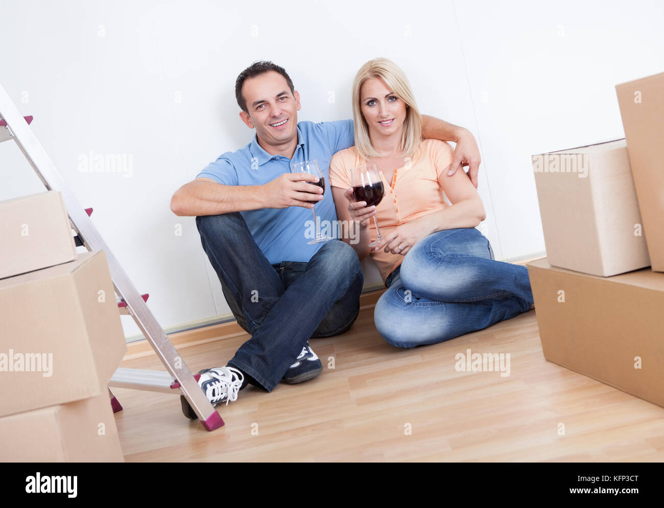 Ehepaar sitzt zwischen Kartons und Weinglas, drinnen zu halten Stockfoto