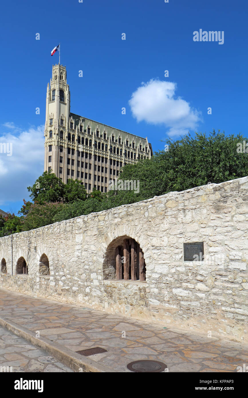 Wand des langen Baracke des Alamo Mission mit dem historischen Emily Morgan Hotel im Hintergrund in der Innenstadt von San Antonio, Texas Stockfoto