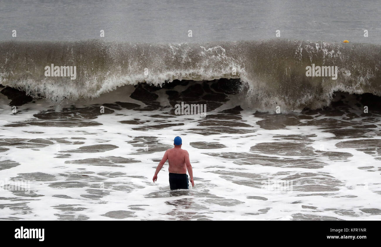 Mutige Schwimmer vom Panama Swimming Club in Whitley Bay, Tyne und Wear, betreten die Nordsee für ein Bad, während riesige Wellen das Ufer wallen. Bilddatum: Dienstag, 31. Oktober 2017. Bildnachweis sollte lauten: Owen Humphreys/PA Wire Stockfoto