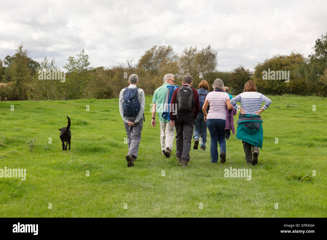 Gruppe von Menschen, die den Hund auf dem Land in Großbritannien von der Rückansicht zu Fuß; Northmoor, Oxfordshire England Großbritannien Stockfoto