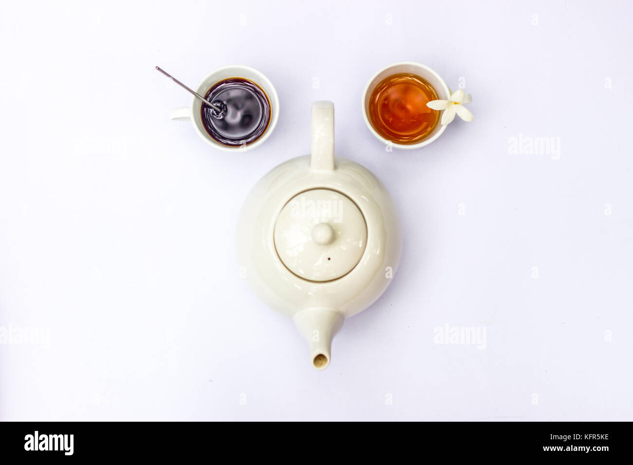 Blick von oben auf die kreative Zusammensetzung auf die Tasse Kaffee, Tee und Weisse Teekanne auf weißem Hintergrund. in Form der menschlichen lustige Parodie Gesicht. Stockfoto