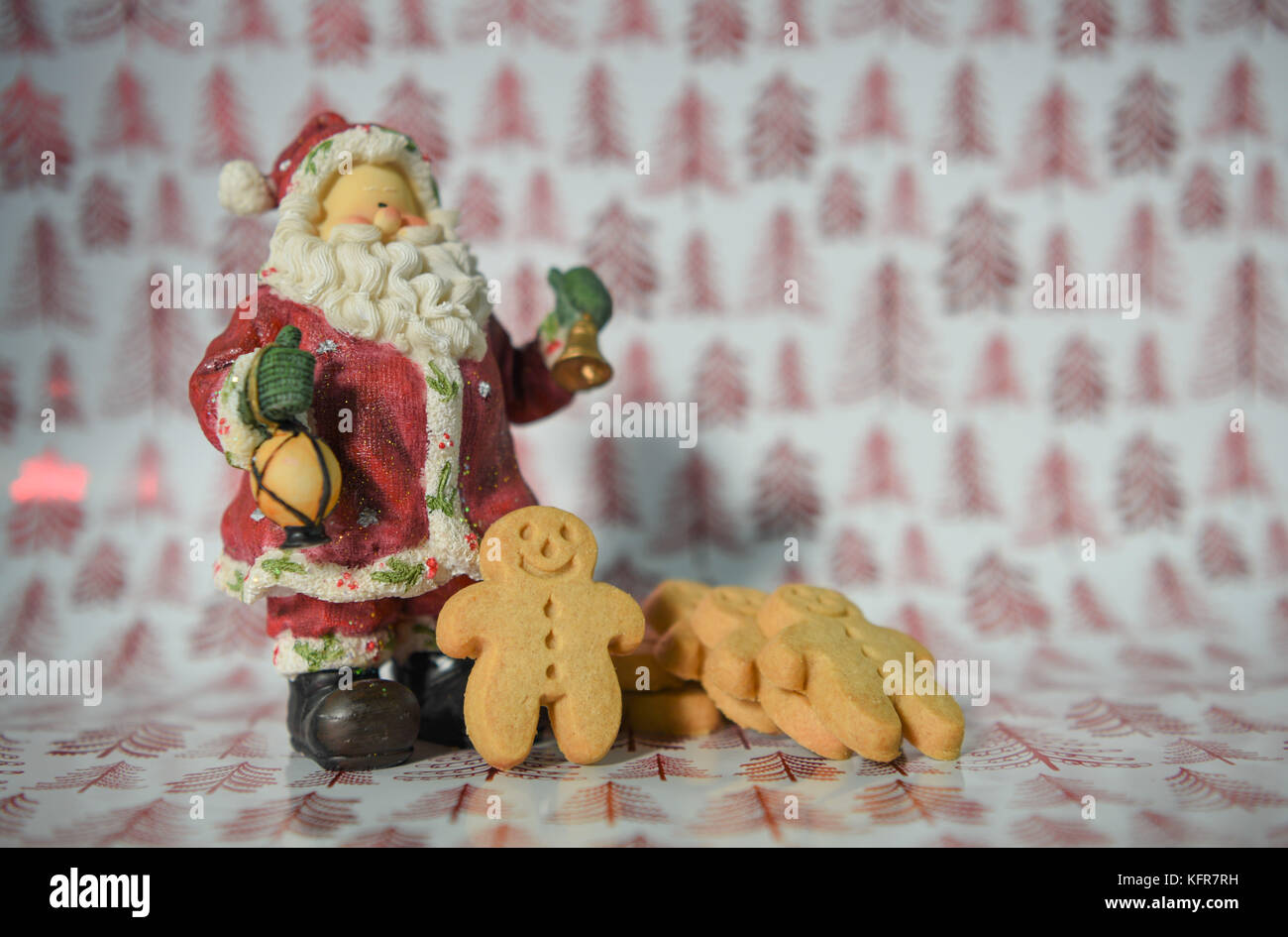Bunte Weihnachten essen Fotografie Bild mit Rot glänzenden Weihnachtsbaum Geschenkpapier Hintergrund und Gingerbread man Kekse mit Santa Claus ornament Stockfoto