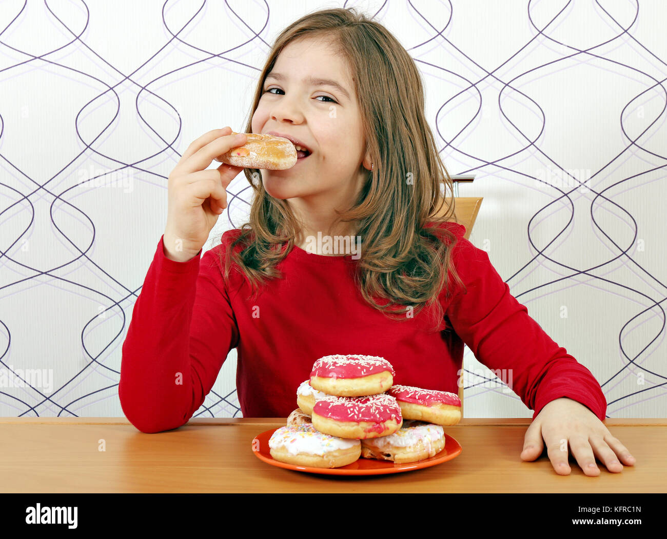 Kleines Mädchen hungrig essen süß Donuts Stockfoto
