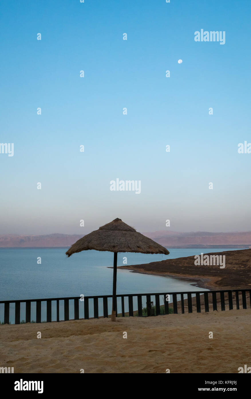 Am frühen Morgen mit Mond am Himmel in der Holiday Inn Dead Sea Resort, keine Leute am Strand und Stroh Regenschirm, Jordanien, Naher Osten Stockfoto