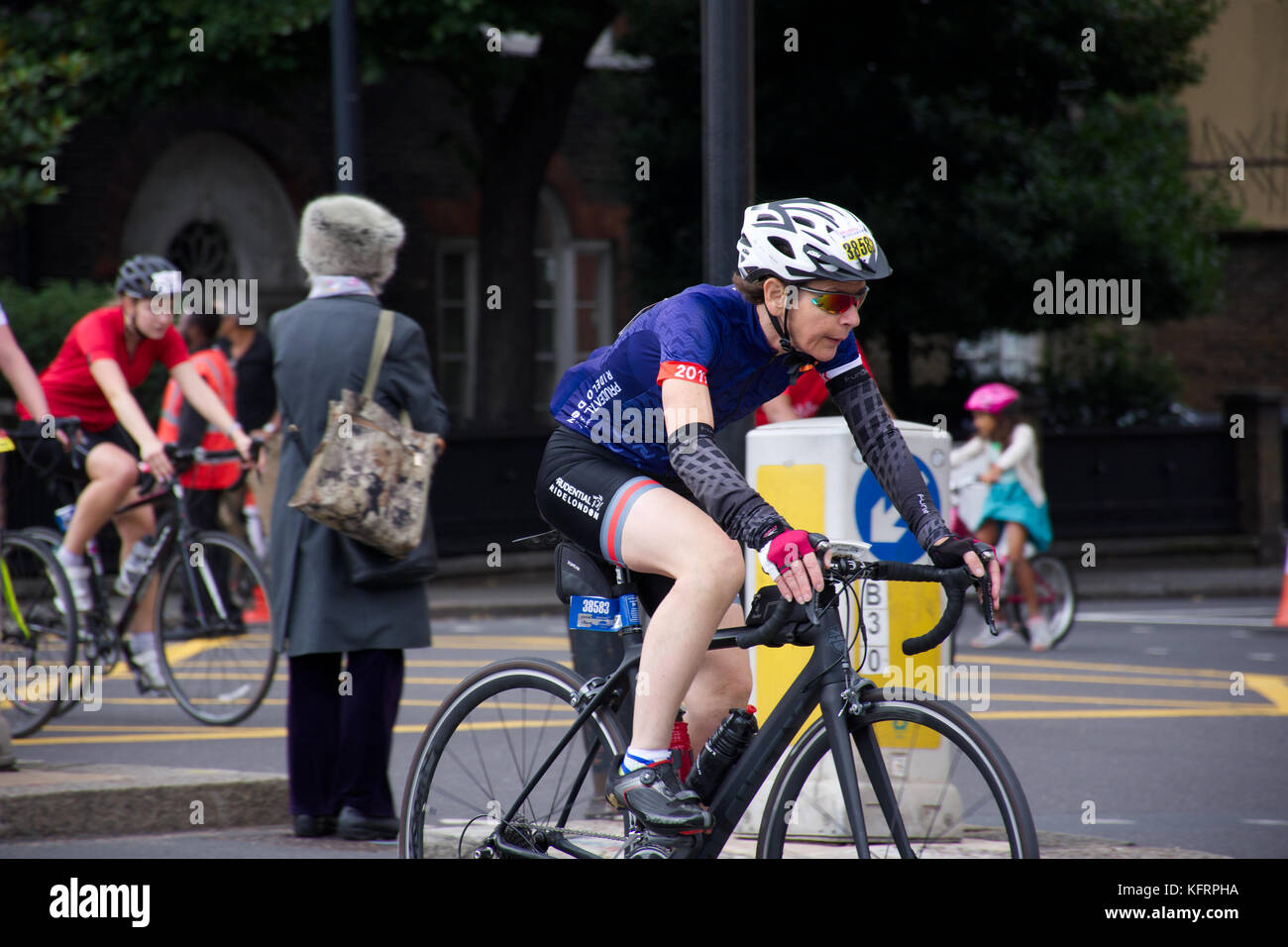Frau mittleren Alters, die in den weißen Helm, schwarz Fahrrad auf jährlichen London prudential Radrennen. London, Vereinigtes Königreich, Sommer 2017. Stockfoto