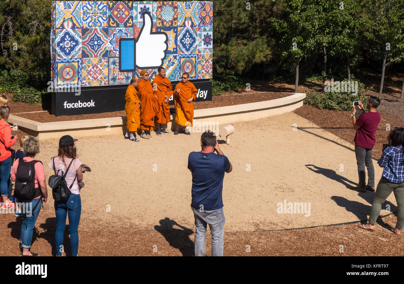 Facebook-Hauptquartier Daumen hoch Unterschreiben mit buddhistischen Mönchen und anderen Touristen fotografieren am Eingang am 1 Hacker Way In Menlo Park, Kalifornien Stockfoto