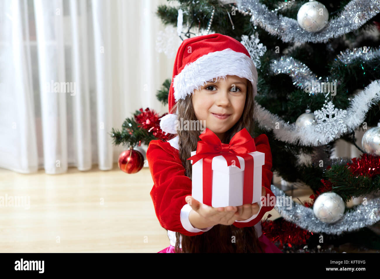 Feier von Weihnachten, Winter Urlaub und Personen Konzept. Glückliche junge Mädchen mit Geschenken in den Feldern in der Nähe eines geschmückten Weihnachtsbaum zu Hause stehend Stockfoto