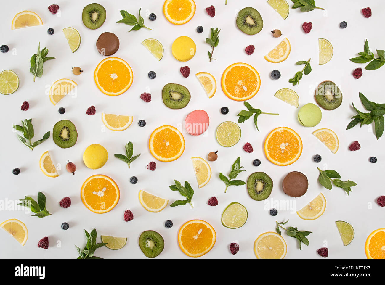 Flach Stillleben mit Macarons, Beeren, Minze und Zitrus- und andere Früchte: orange Frucht; Kalk; Zitrone, Kiwi auf weißem Hintergrund. Pop Art Trend noch Stockfoto