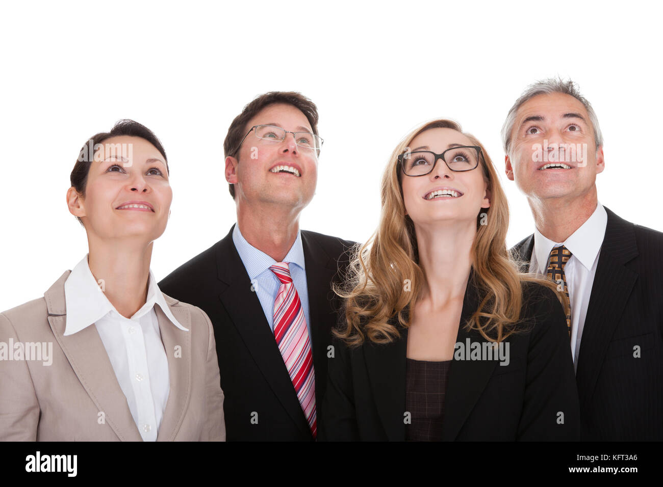 Vier glückliche vielfältige professionelle Geschäftspartner in einer Reihe auf der Suche nach oben mit einem Lächeln, isoliert auf weiss Stockfoto