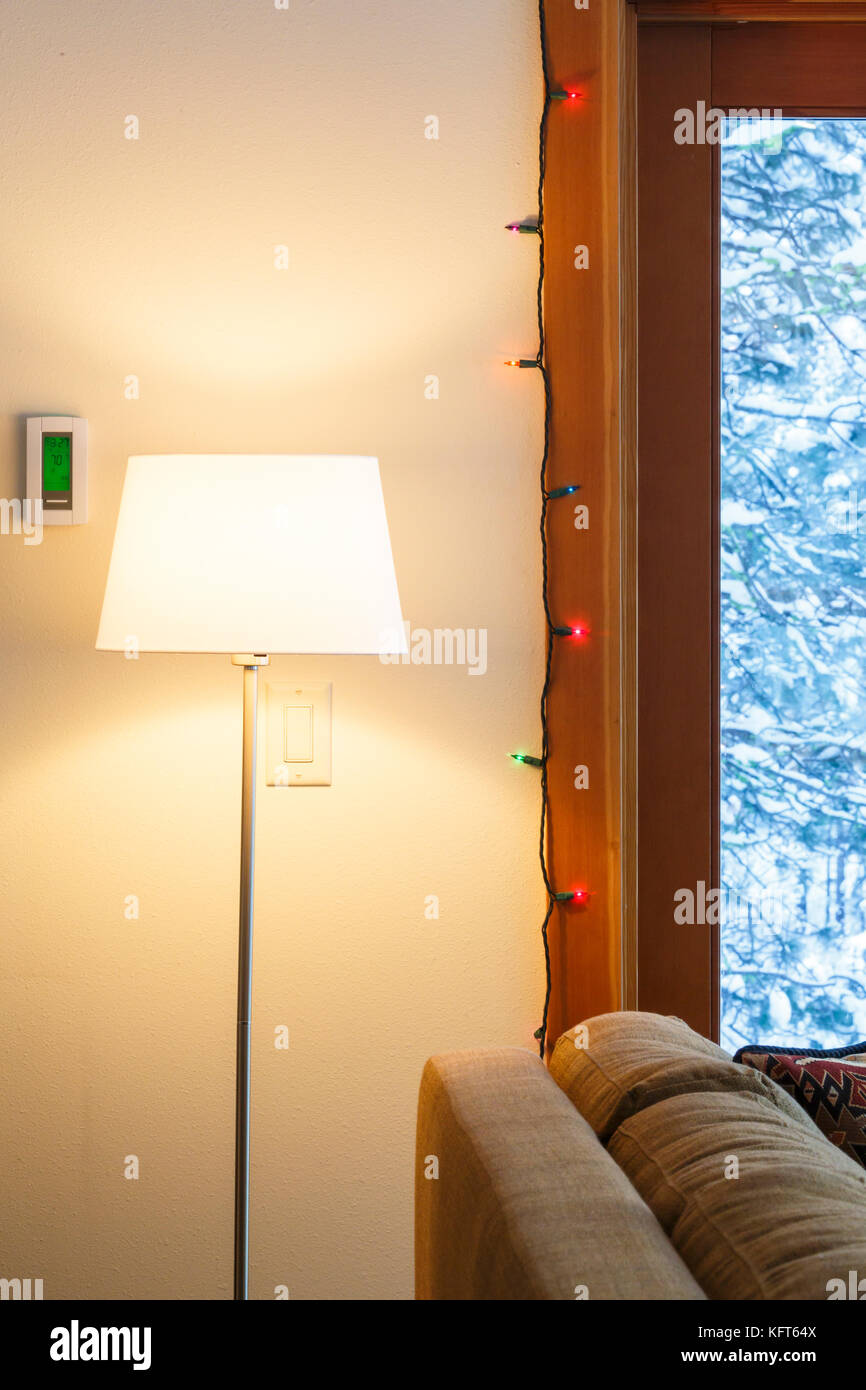Warme Wohnung Wohnzimmer Interieur mit digitalen elektronischen Thermostat, Stehleuchte, Weihnachtsbeleuchtung und durch die verschneite Landschaft zu Windows anzeigen Stockfoto