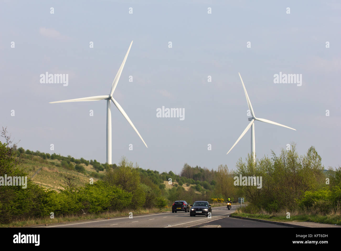 Zwei Windkraftanlagen Erzeugung erneuerbarer Energien oberhalb einer Straße in South Yorkshire, Großbritannien Stockfoto