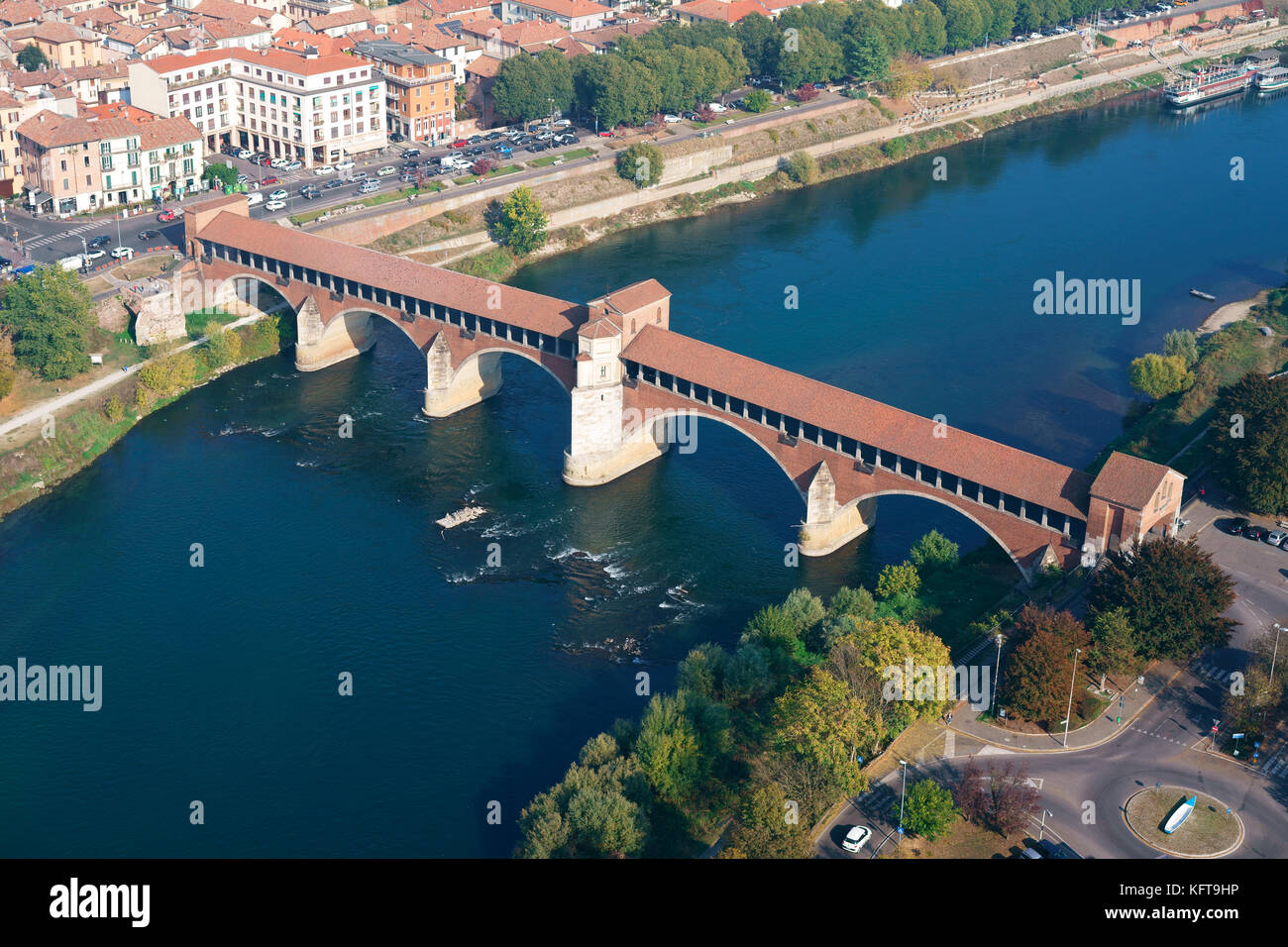 LUFTAUFNAHME. Historische überdachte Brücke (Ponte Coperto) über den Fluss Tessin, in der Mitte steht eine kleine Kapelle. Pavia, Lombardei, Italien. Stockfoto