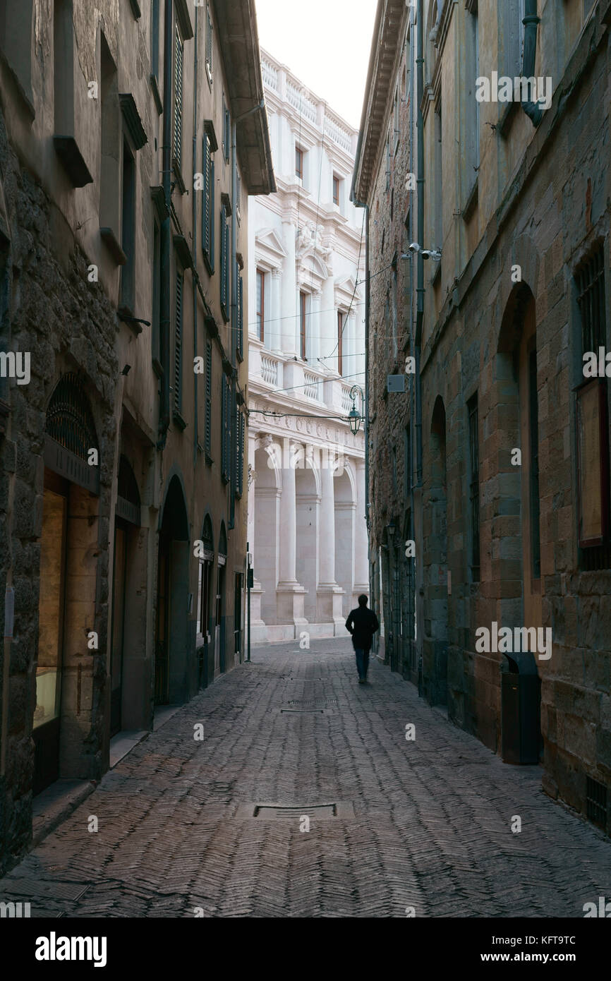 Silhouette eines Mannes, der auf einer verlassenen schmalen Straße läuft. Città Alta (Oberstadt), Bergamo, Provinz Bergamo, Lombardei, Italien. Stockfoto