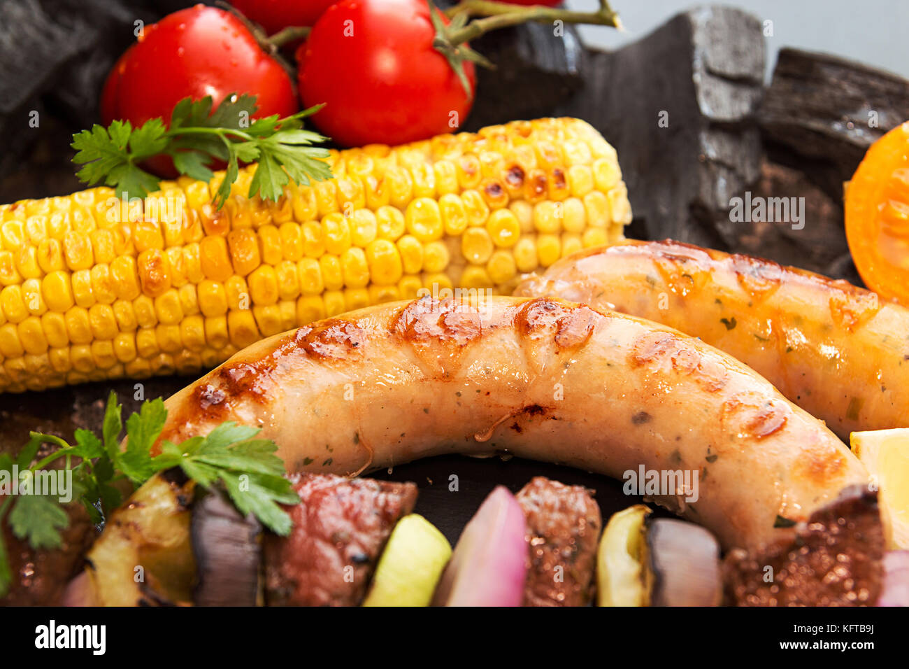 Sortierte Köstliches vom Grill Grill Fleisch mit Gemüse. Rindfleisch Steaks vom Grill mit würzigen Würstchen, Rindfleisch Kebabs, Mais, Cherry Tomaten, Pfeffer, Scheiben Stockfoto