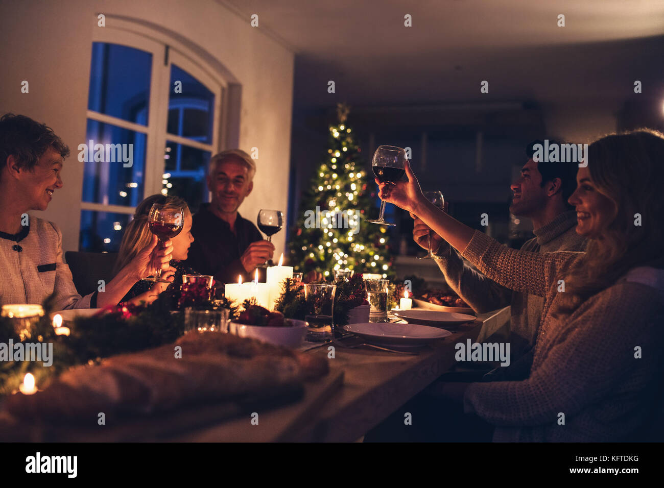 Erweiterte Familie toasten Wein zum Weihnachtsessen. Happy Family weihnachten Candle light Dinner zu geniessen zu Hause. Stockfoto