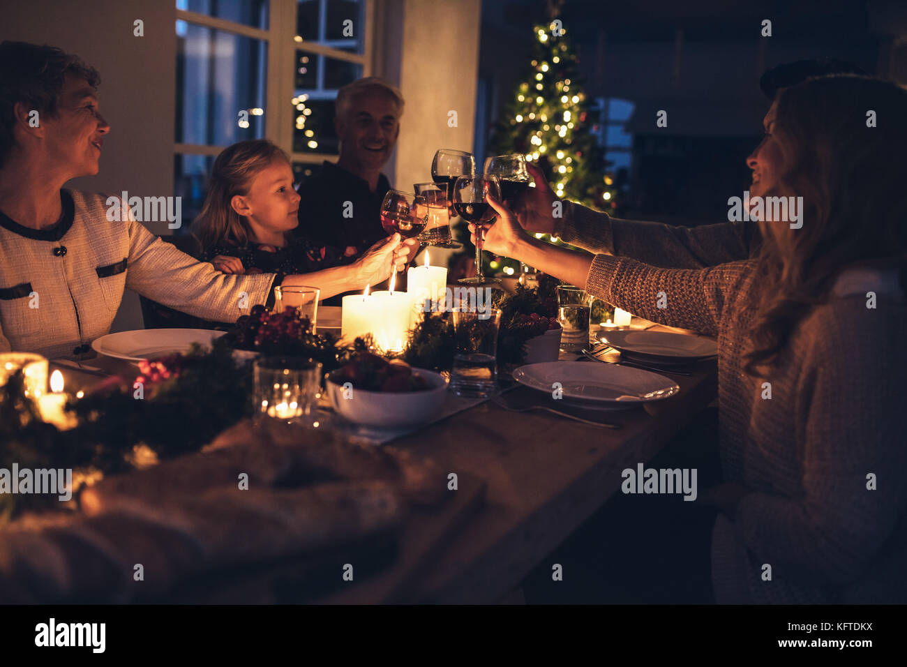 Glückliche Großfamilie toasten Getränke während Weihnachten Abendessen zu Hause im Wohnzimmer. Die Familie feiert Weihnachten zusammen. Stockfoto