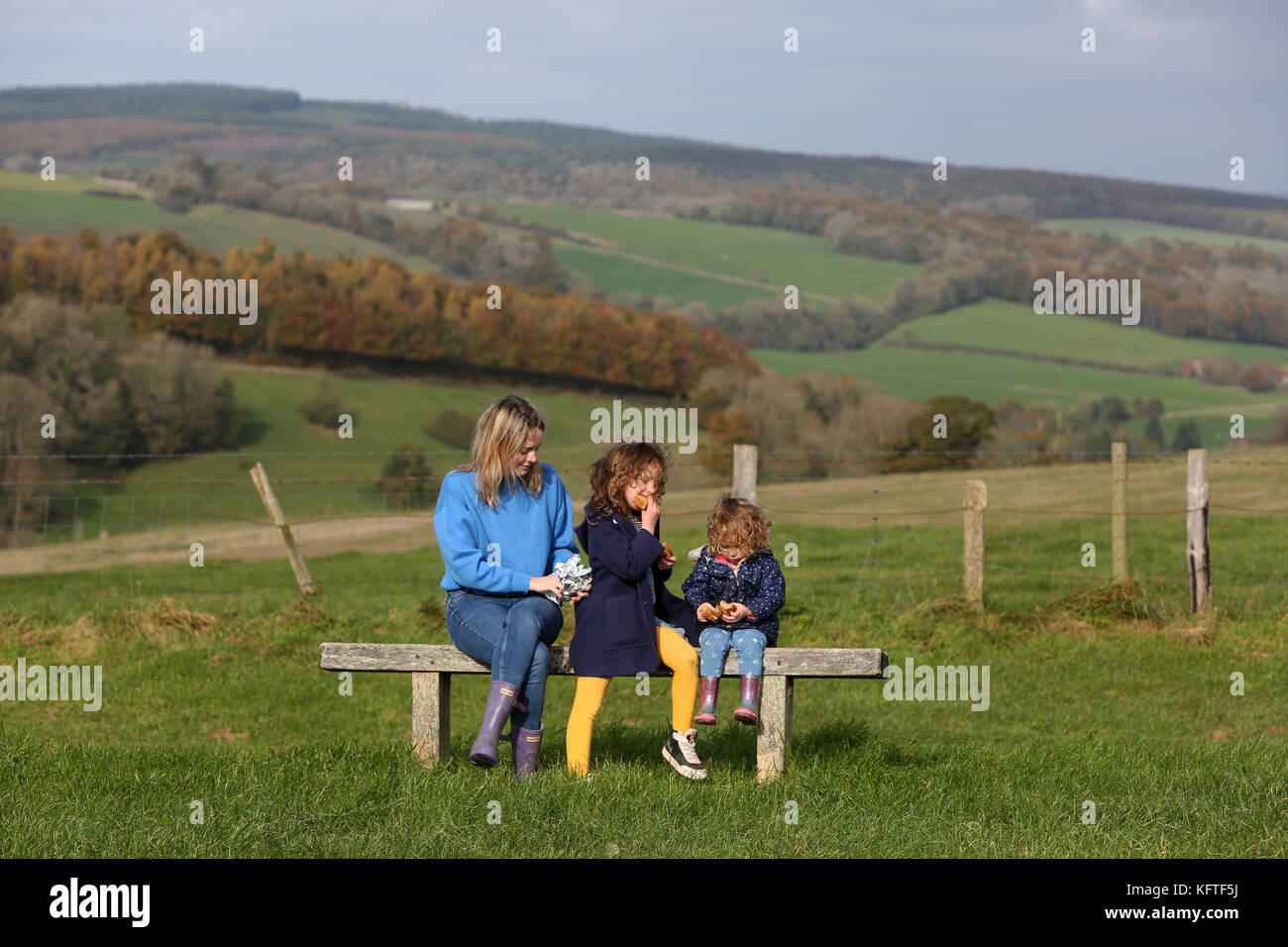 Eine Mutter und ihre zwei Kinder im Bild bei einem Picknick und ein Sandwich auf der South Downs in der Nähe von Goodwood, West Sussex, UK. Stockfoto