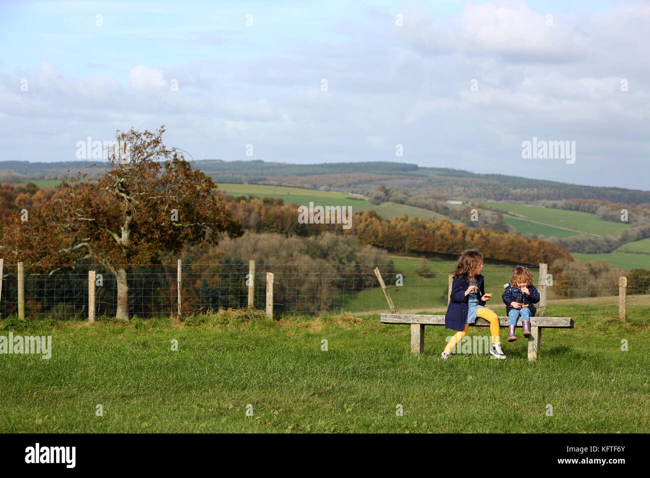 Eine Mutter und ihre zwei Kinder im Bild bei einem Picknick und ein Sandwich auf der South Downs in der Nähe von Goodwood, West Sussex, UK. Stockfoto