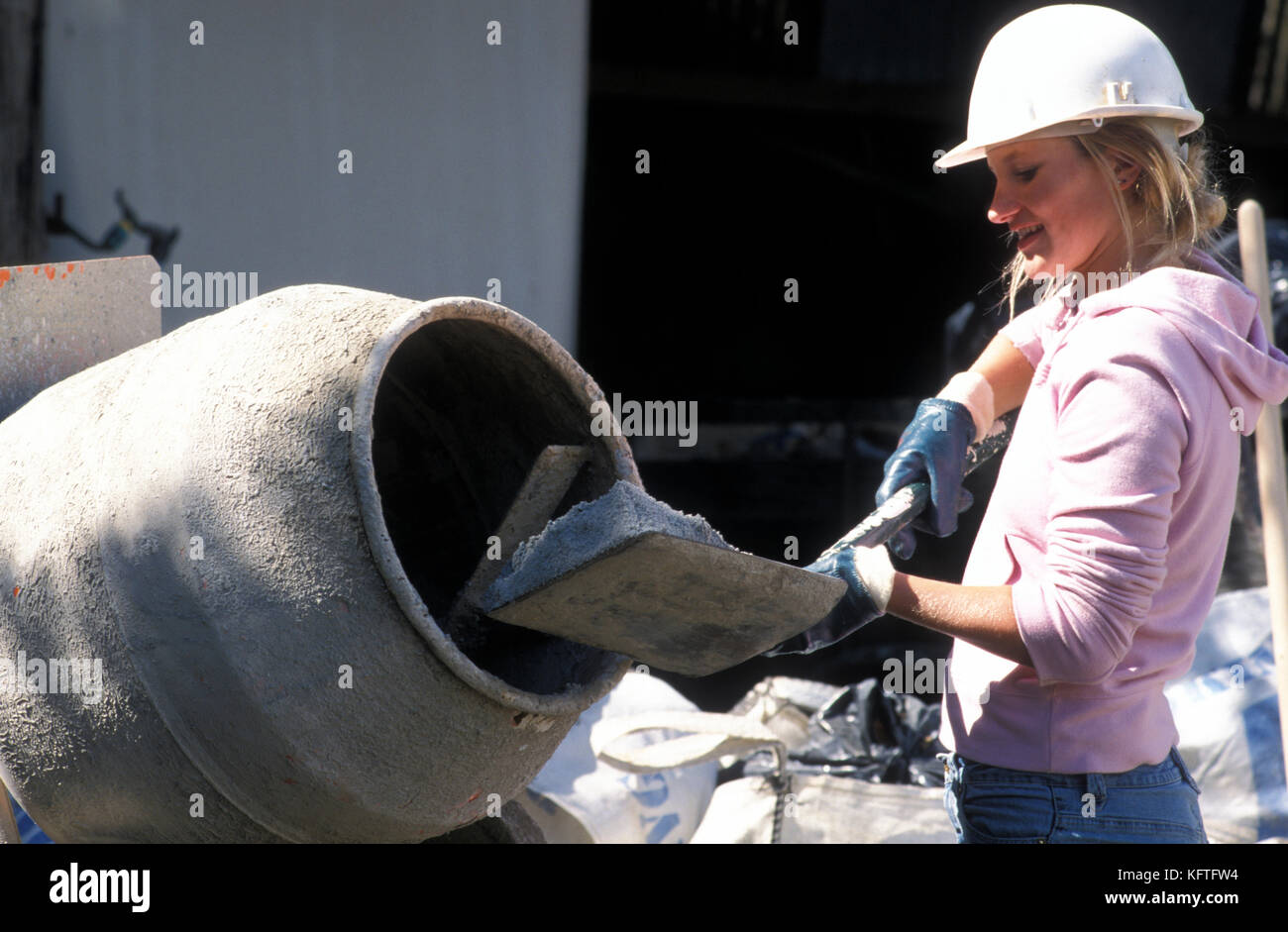 Junge weibliche Arbeiter auf der Baustelle Befüllen cement Mixer Stockfoto