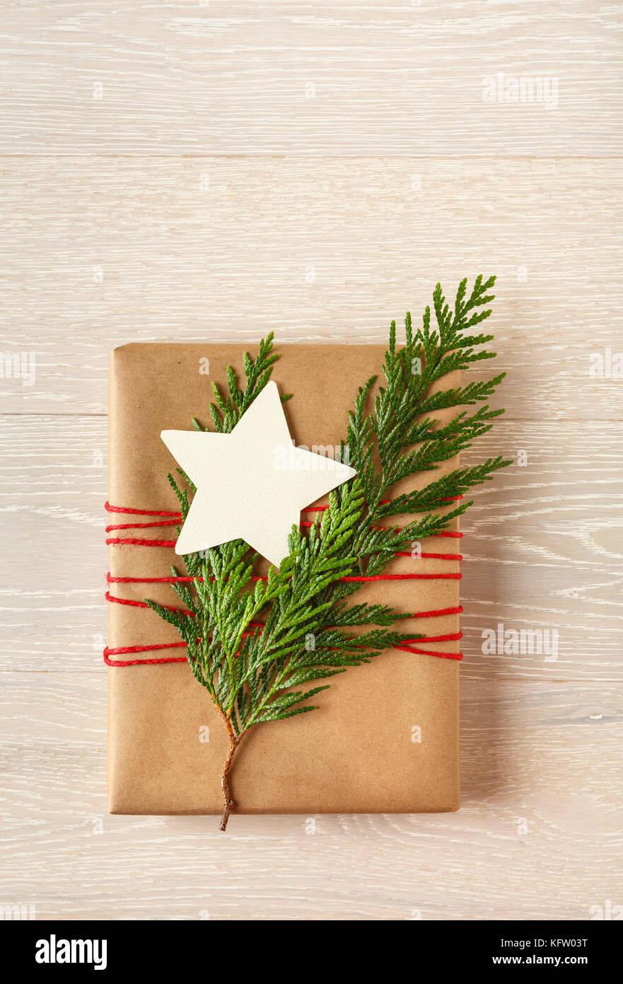Weihnachten Geschenk in recycelten Verpackung Papier mit natürlichen Evergreen Dekorationen und eine leere umhüllt, sternförmige Geschenkanhänger auf Holz Hintergrund Stockfoto