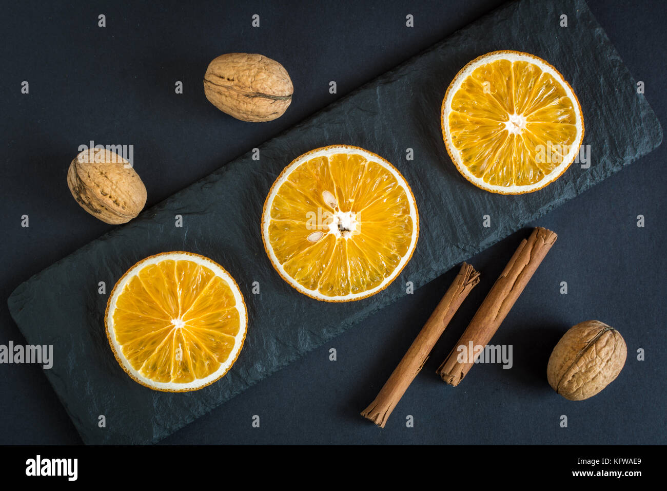 Trocknen orangenscheiben Früchten, Nüssen und Zimt auf schwarzem Schiefer Hintergrund. Stockfoto