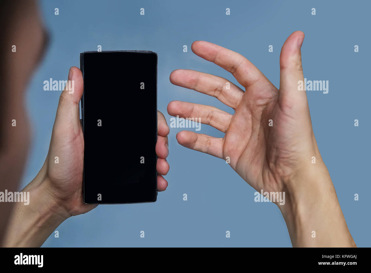 Der Typ schaut sein Telefon mit Verwirrung an. Sprechen im Video-Chat auf dem Handy. Leer für Bild. Das schwarze Telefon. Stockfoto