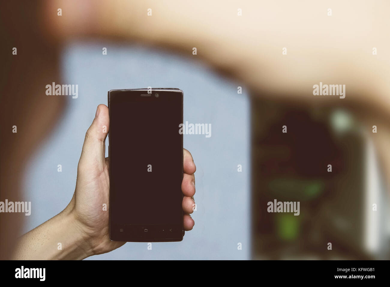Der Kerl hält das Telefon in einer durchdachten darstellen. Kerl, selfie. Fotos auf dem Smartphone in der Wohnung. Stockfoto