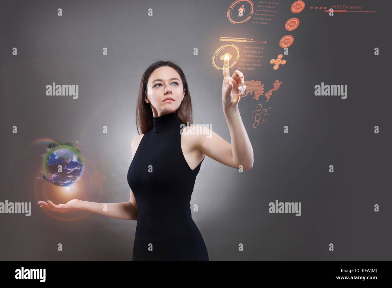 Eine junge Frau in einem schwarzen High-tech-Kleid, und drücken Sie die Hand gegen einen holografischen Bildschirm Stockfoto