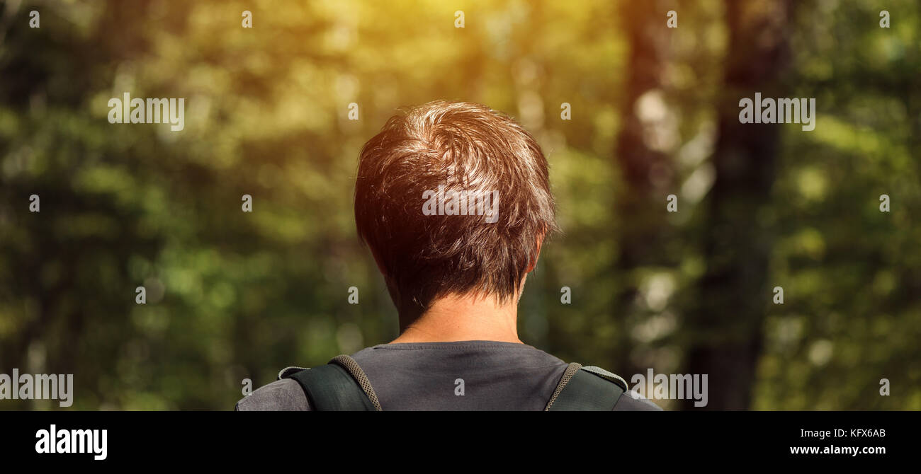 Ansicht der Rückseite des Erwachsenen kaukasischen Mann mit Rucksack beim Spaziergang im Park auf sonnigen Sommernachmittag. gesunder Lebensstil, Erholung und Natur liebenden Stockfoto