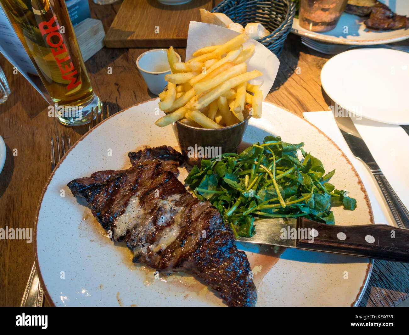 Mittag abgeflacht in der Pfanne gebratene bavette Steak mit Pommes frites serviert gebutterte Brunnenkresse und serviert mit Meteor Bier d'Alsace Stockfoto