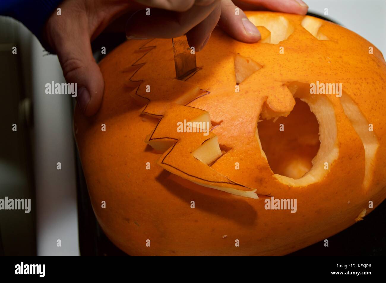 In der Nähe der Hand des Menschen Carving furchtsames Gesicht in Kürbis für Halloween, Großbritannien Stockfoto