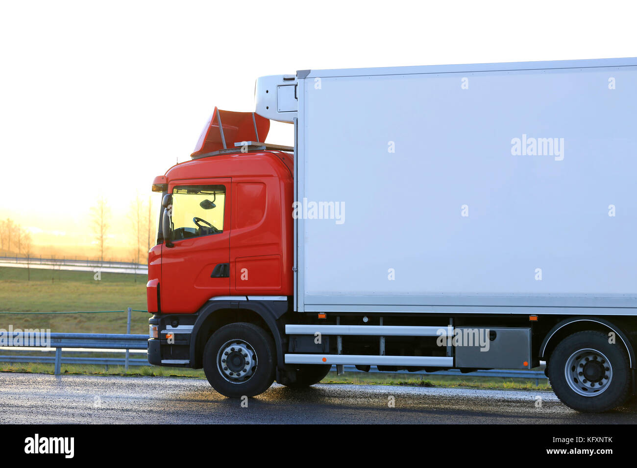 Red Temperaturgeregelte Ladung Fahrzeug durch einen Truck Stop ist bereit, am Morgen bei Sonnenaufgang zu gehen. Stockfoto