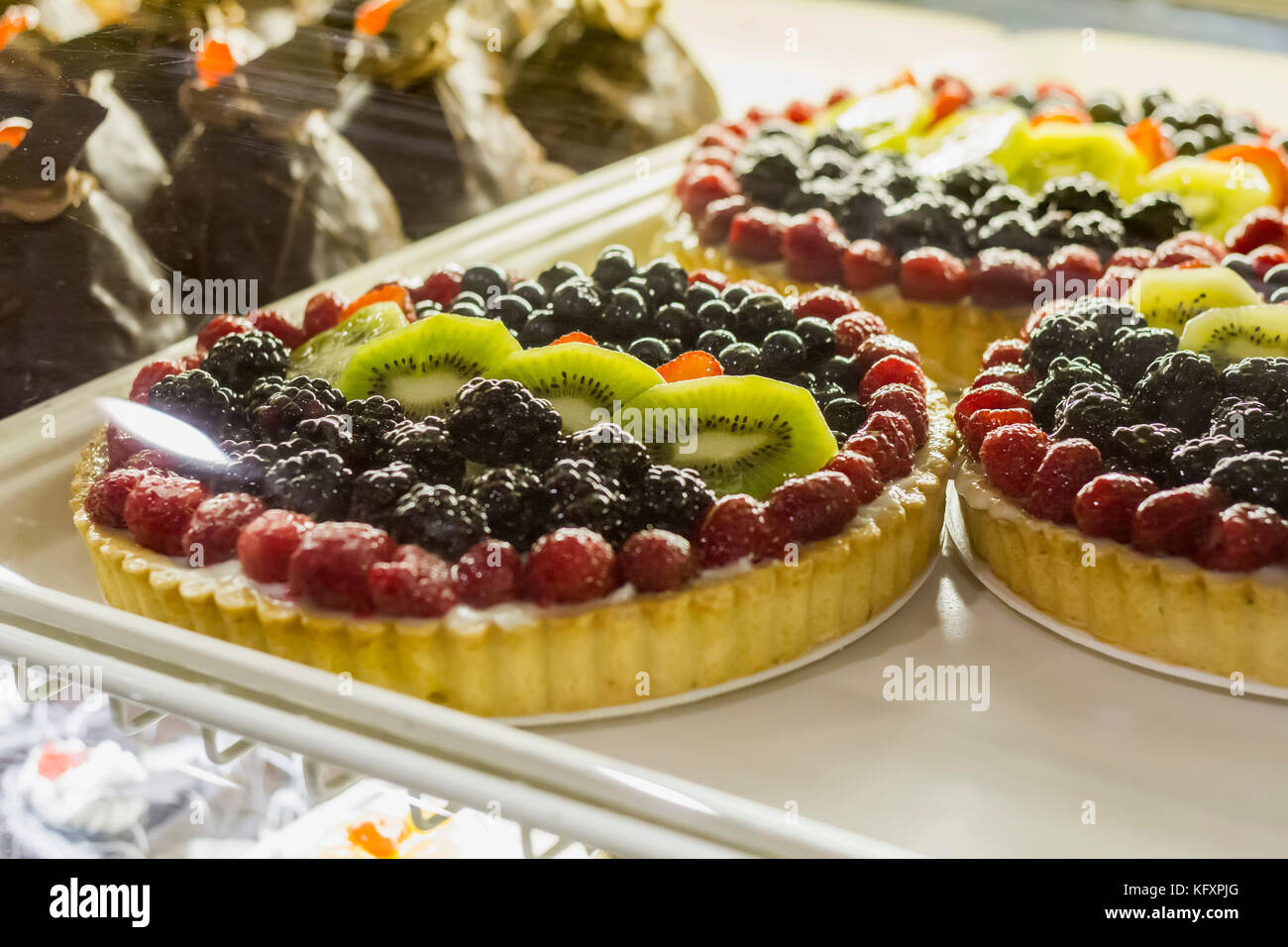 Frische süße Kuchen mit Johannisbeeren und Erdbeeren Beeren im Pastry Shop-Glas-Display an der Spitze Stockfoto