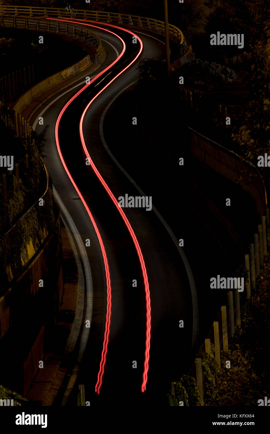 Rotes Geschwindigkeitslicht von einem Auto auf kurvenverlaufter Strecke (Madrid, Spanien). Stockfoto