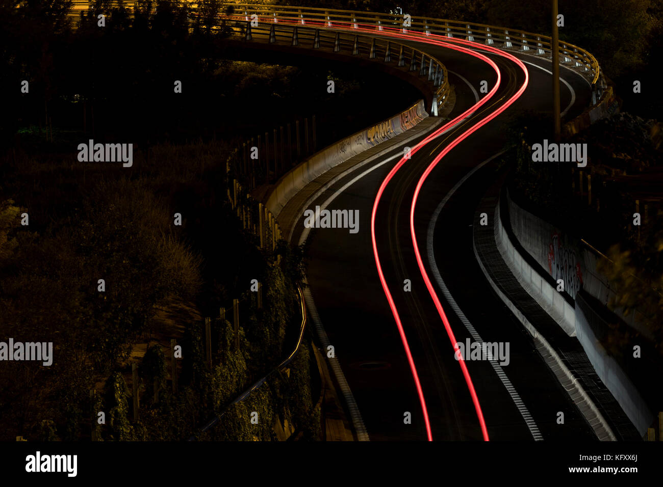 Einsames Auto, das nachts eine Route mit Geschwindigkeitslichtern malt (Madrid, Spanien). Stockfoto