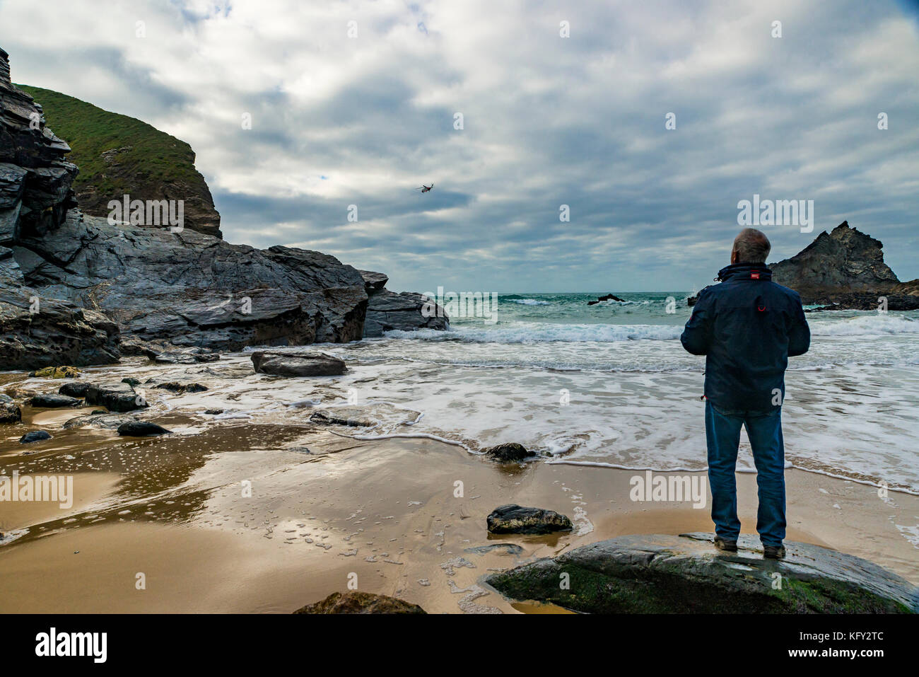 Die Menschen beobachten, wie ein Helikopter der Küstenwache swoops und schwebt um bedruthen Schritte in Cornwall, Großbritannien Stockfoto