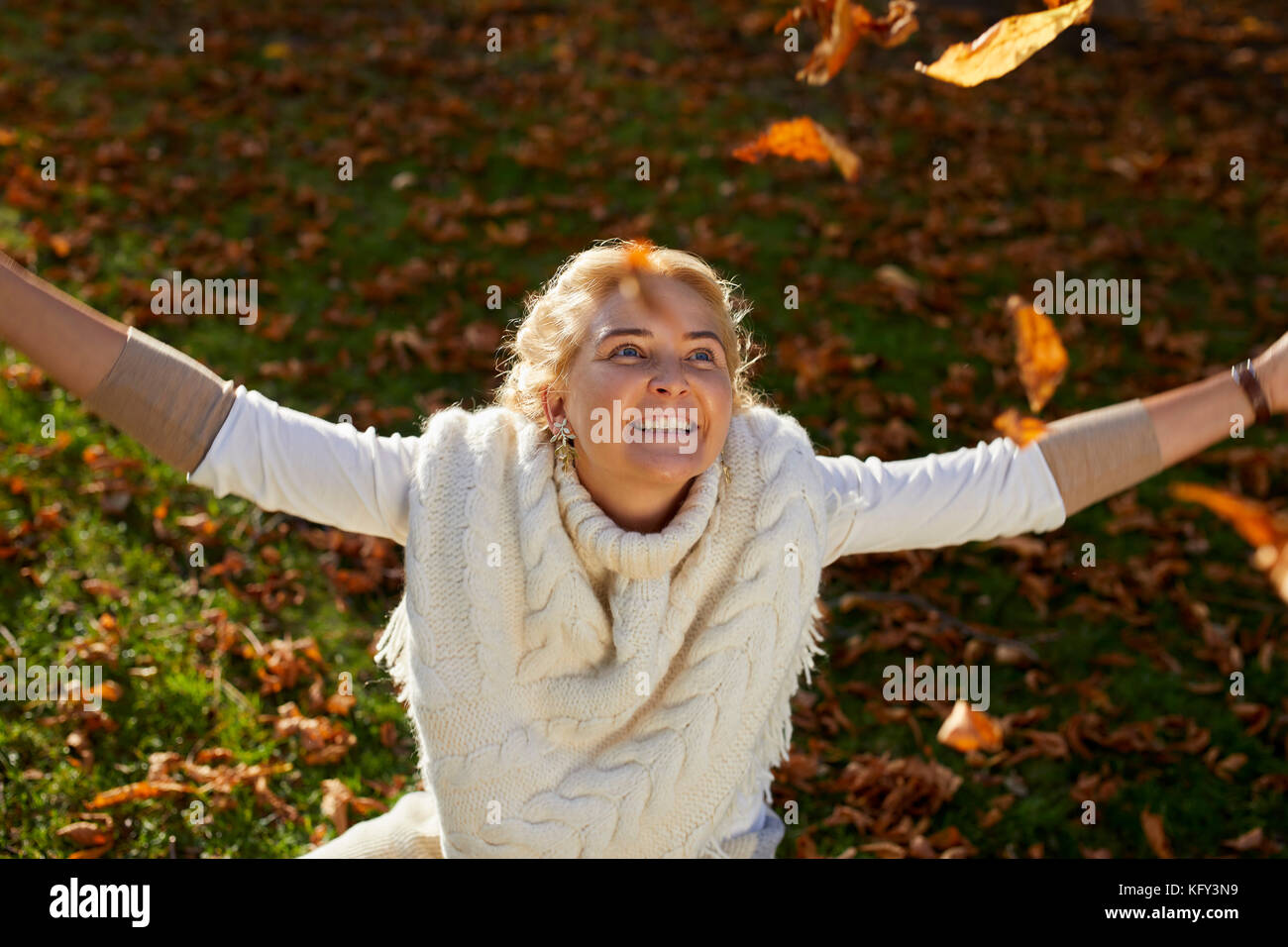 Frau spielen mit Blättern im Freien Stockfoto